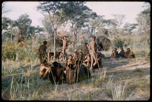 Men performing a curing dance, with a group of people sitting and watching them