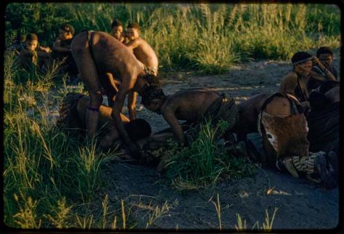 /Gunda treated by medicine men, with a group of people watching them