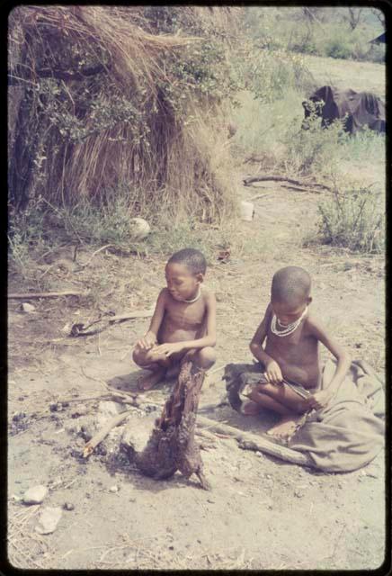 Two children sitting by ashes of fire