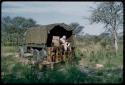 Robert Story sitting and attending to something in a truck, with a group of people nearby