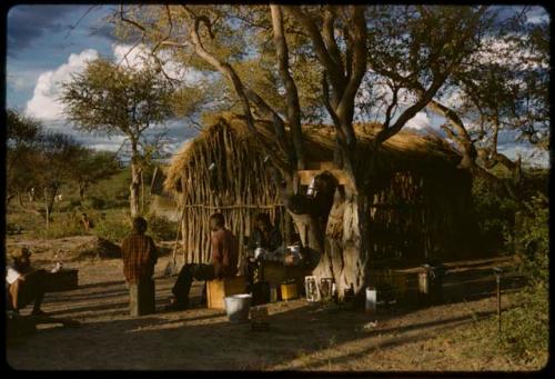 Exterior of a cookhouse, with people sitting nearby