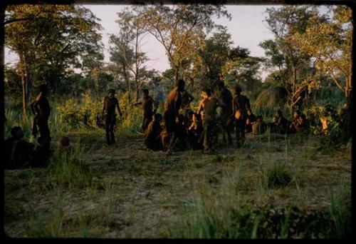 Men performing a curing dance, with a group of people sitting and watching them