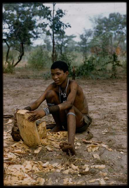 N!amshi holding a hollowed log to make a //guashi