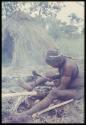 Man from Samangaigai making an axe, sitting in front of a skerm