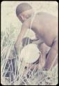 Man pouring something from a pail, seen from behind