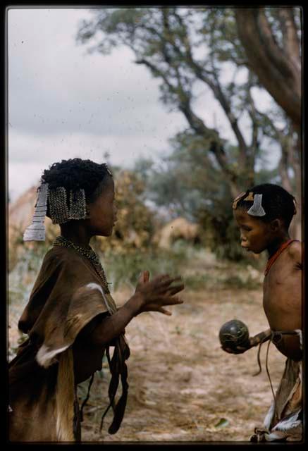 Two children playing !’hu kuitzi (veldkos game); one is holding a veldkos
