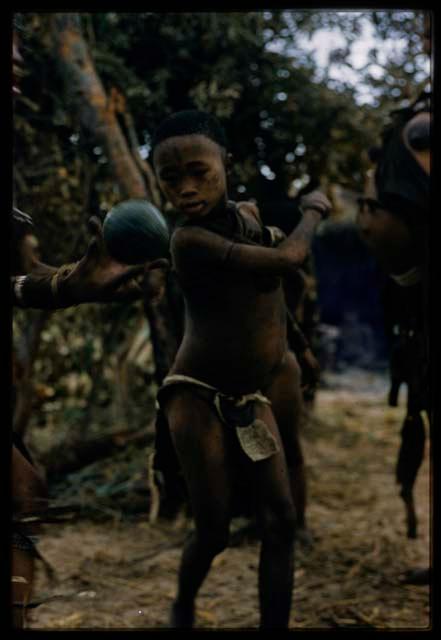 Child looking poised to swat a veldkos, !’hu kuitzi (veldkos game)