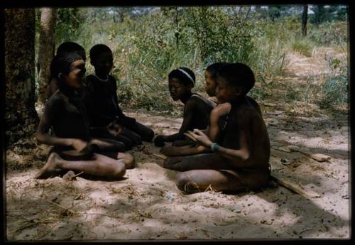 Group of children sitting in facing rows, probably playing a game