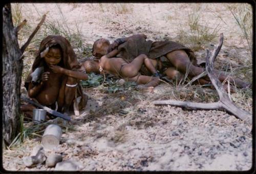 Di!ai and a baby lying asleep, with another child covered with kaross sitting in the foreground