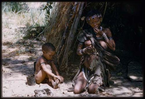 Di!ai eating, seated with a child in front of a skerm