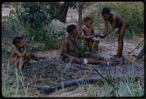 !U giving mangetti nuts to her son, /Gaishay, with her other children sitting nearby