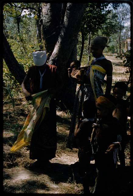 N!ai and ≠Nisa wearing Western clothes, with three children nearby