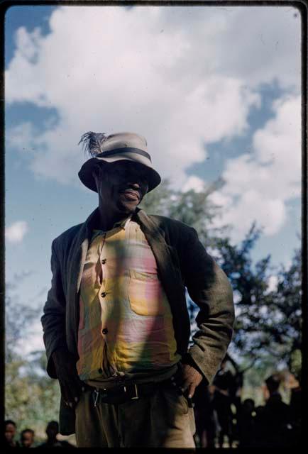 /Ti!kay wearing Western clothes (jacket, plaid shirt, and felt hat with feather)