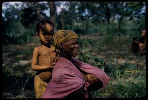 /Ti!kay's wife wearing a kerchief, with a child standing behind her