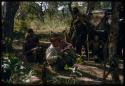 Group of men gathered near a truck, including "Crooked /Qui" and !Kxao Lame sitting and wearing western clothes