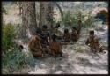 Group of people gathered under a tree at the edge of mangetti forest