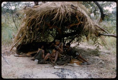 Women and children under a skerm built for shade