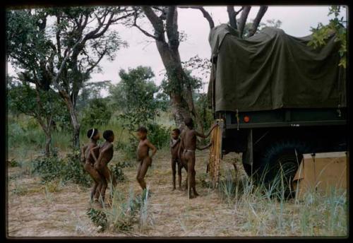 Group of children standing near the back of a truck