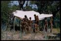 Group of people (mostly children) getting water beside a canvas