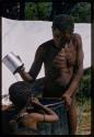 Gau pouring water and //Kushay standing opposite him, with canvas shown in the background