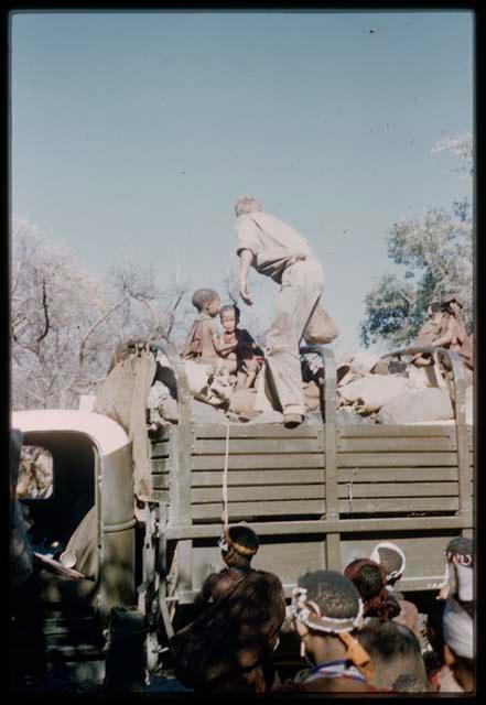 Group of people and John Marshall riding on a gree expedition truck to get water