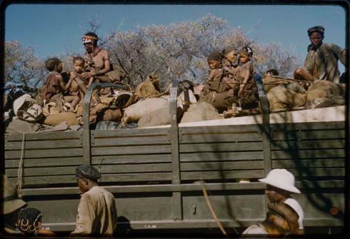 Group of people and John Marshall riding on a green expedition truck  to get water