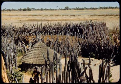 People, round huts and fence inside a kraal, view from the top of the expedition truck