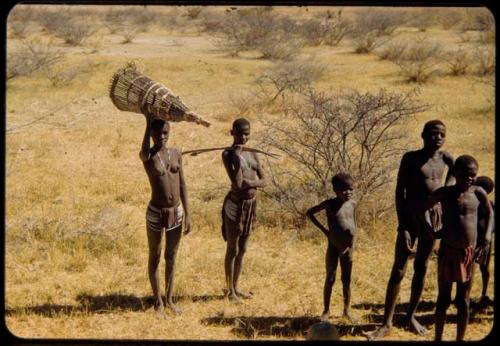 Group of people going fishing, one carrying a fish trap on her head