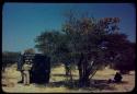 Laurence Marshall standing by an expedition truck, probably about to make camp