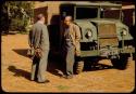 Charles Koch standing with an unidentified person next to an expedition truck