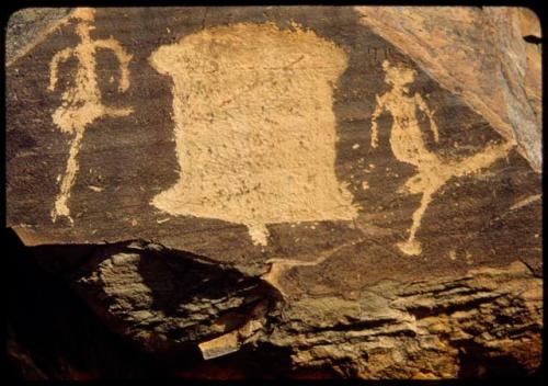 Petroglyphs of a bell-like figure (possibly an animal skin) and two human figures at Scho-Scho