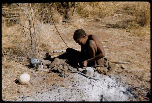 Arrow: ≠Gao (husband of Khwo//o-Gasa) working, probably on an arrow point, with an Ovambo pot and assegai on the ground near him