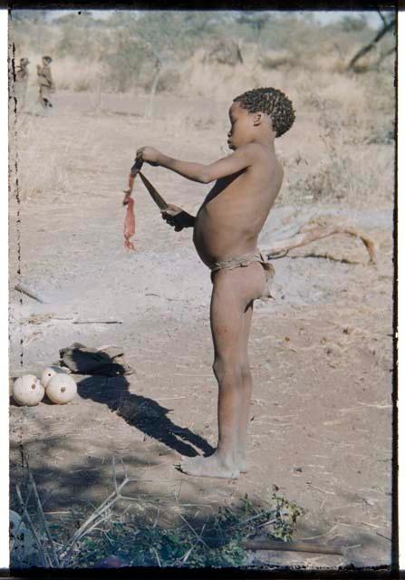 Children, Eating: Tsamgao (son of ≠Toma and !U) standing and cutting a piece of meat with a knife