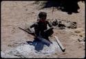 Children, Eating: Girl cooking meat in ashes with a fire paddle