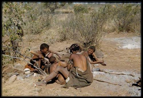 Children, Mothers nursing babies: //Khuga (wife of !Naishi, headman of Band 5) pounding something with a mortar and pestle, sitting with Khwo//o (mother of "/Gao Music" and /Goishay, half-sister of "/Qui Navel" in Band 1) and !U with !Ungka Norna (soon after her hair was cut)