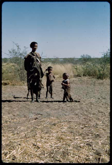 Children, Mothers nursing babies: !Gisa (wife of //Ao) standing with her baby daughter, Khuan//a (after her hair was cut), and /Qui (son of Gau and Khuan//a)