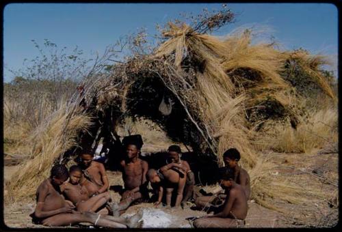 Children, Mothers nursing babies: Gau (of Band 2) sitting with his family by their skerm, left to right: ≠Toma (son of Gau and Be), ≠Gao (son of Gau and Be), Be, Gau, Khuan//a (Gau's second wife) and her son /Qui, Gunda (son of Khuan//a by a former marriage with Bo) and !Naishi (son of Gau and Be)