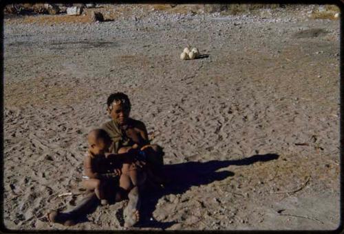 Children, Mothers nursing babies: Woman sitting and nursing two babies, with four ostrich eggs in background