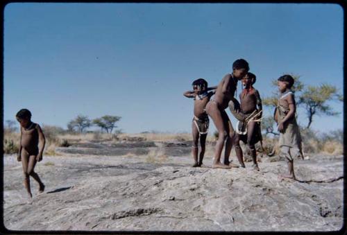 Children, Groups, play: Group of boys and girls playing on a termite mound, including ≠Gisa (daughter of ≠Gao and Khwo//o-/gasa) wearing ornaments and white beads