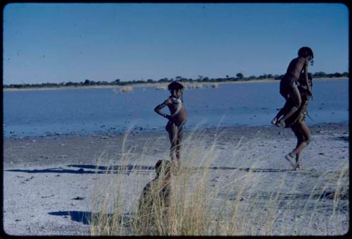 Children, Groups, play: Girls playing "piggyback" by a pan with water in it