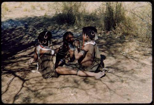 Children, Groups, play: Three girls sitting, one making a string figure