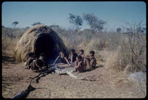 Marriage: N!ai and /Gunda sitting with guests in front of their skerm the day after their wedding, including ≠Gao and ≠Toma (Gau's sons), Tsamgao (≠Toma's son), "Little N!ai," Xama (daughter of "Gao Helmet") and ≠Gisa (daughter of ≠Gao and / Khwo//o-/Gasa in Band 4)