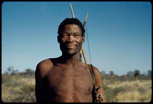 Portraits: /Ti!kay standing, with his hunting bag over his shoulder, close-up