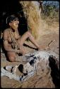 Portraits: Woman sitting by the ashes of a fire in front of a skerm