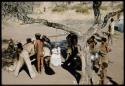 Expedition, Cooking: Women standing under a tree in the cooking area in the camp, with Nagani standing and John Marshall leaning over a table near them