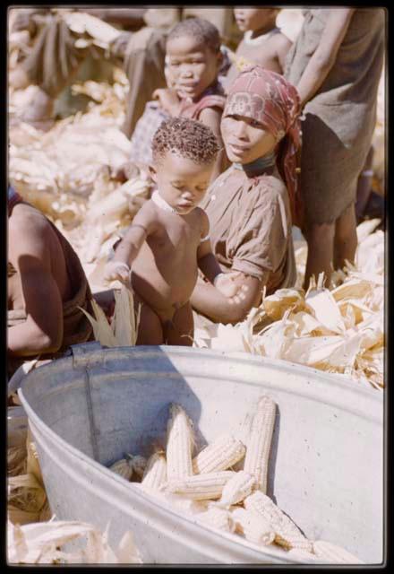 Expedition, Metzger: Mother sitting with her child next to a metal tub of corn