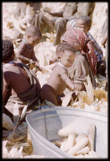 Expedition, Metzger: Mother sitting with her child next to a metal tub of corn