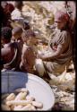 Expedition, Metzger: Mother sitting with her child next to a metal tub of corn
