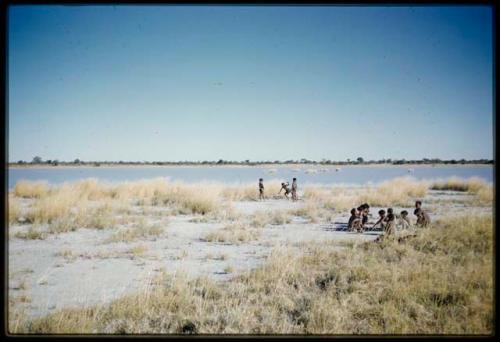 Scenery, Pan: Group of boys sitting, with a group of girls standing at the edge of Gautscha Pan in the background, distant view