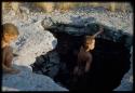 Scenery, "Water Hole": Boy standing inside a waterhole, with another boy sitting on the edge of it